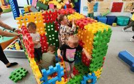 Dzieci budują dom z plastikowych klock&oacute;w.