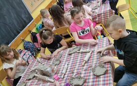 Uczniowie z kl. 0 lepią gliniane miseczki.