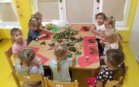 Dziewczynki tworzą jesienne prace plastyczne.