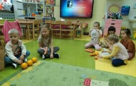 Dzieci liczą pomarańczowe warzywa i owoce.
