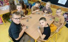 Uczniowie przy stoliku nr 2 szkliwią glinianego jeża