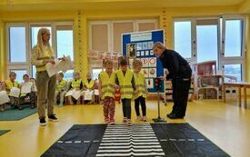 Pani policjantka przypomina dziewczynkom na jakim świetle przechodzi się po pasach.