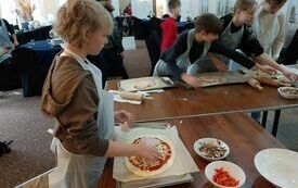 Uczestnicy warsztat&oacute;w dodaja do pizzy dodatki
