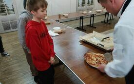 Pan Jacek kroi upieczoną pizzę Michałowi