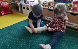 Szymcio z grupy ,,Motylki'' bandażuje nogę Wiktorii.