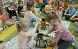 Dzieci wsypują ziemię do doniczek.