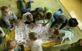 Chłopcy z zer&oacute;wki tworzą plakat WITAJ WIOSNO.