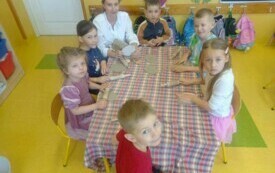 Pani Michasia i dzieci przy 1 stoliczku lepią gliniane jajka.