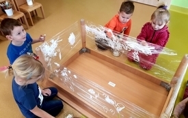 Przedszkolaki z grupy Żabek malują zimowe obrazy na folii.